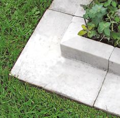 a cement bench sitting on top of a grass covered field next to a planter