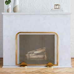 a fireplace with a white brick wall and gold trim around the mantel, which has a painting on it