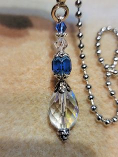 a necklace with blue and clear beads hanging from it's side on a chain