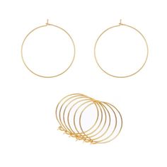 two pairs of gold hoop earrings and four different rings on a white background with the same pair