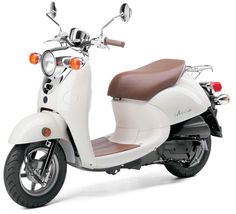 a white scooter with brown leather seat is parked on a white surface,