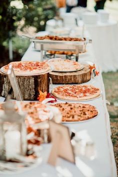 several pizzas are on the table ready to be served at an outdoor wedding reception