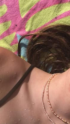 a woman laying on top of a blanket covered in water drops and wet hair with her eyes closed