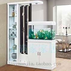 an aquarium in a white cabinet on top of a wooden floor next to a table and chairs