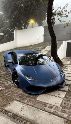 a blue sports car parked in front of a tree