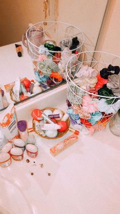 two baskets filled with various items on top of a bathroom counter next to a mirror