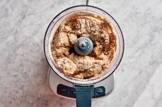 an overhead view of a food processor on a marble counter top with ingredients in it