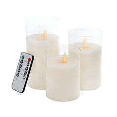 three lit candles with remote control on white background