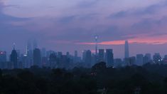 the city skyline is lit up at night with pink and blue hues in the sky