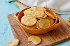 a bowl filled with crackers sitting on top of a wooden cutting board