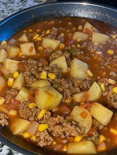 a bowl filled with meat and potatoes on top of a table next to a stove