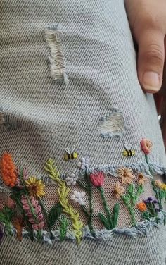 someone is stitching flowers on the side of their pants