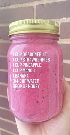 a hand holding up a pink smoothie in a mason jar with instructions on it