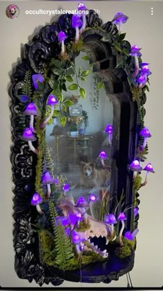 a mirror with purple flowers and plants on the wall next to a corded phone