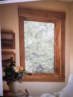 there is a vase with flowers on the table in front of a window that has trees outside