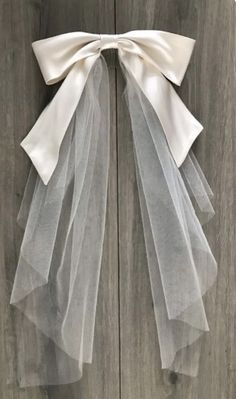 a white bow tied to a wooden door with sheer tulle on the front and back