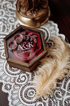 a wooden box sitting on top of a white doily next to a brown feather