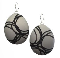 pair of white and black earrings with circular design on the front, hanging from silver earwires