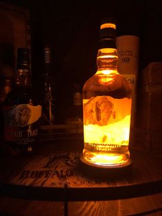 a lit up bottle sitting on top of a wooden table