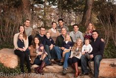 a group of people sitting on top of a rock in front of trees and bushes