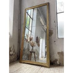 a large mirror sitting on top of a wooden table next to a wall with peeling paint