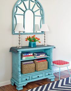 a blue dresser with baskets and a mirror on it's side table in front of a white wall