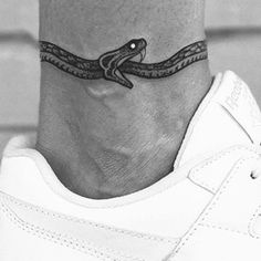 a black and white photo of a foot with a snake tattoo on it