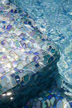 an empty swimming pool with blue and white tiles on the bottom, reflecting water in it