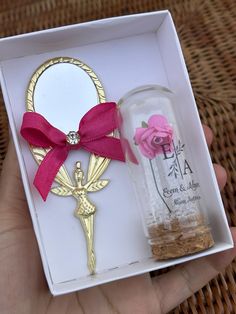 a hand holding a bottle with a rose in it next to a keychain