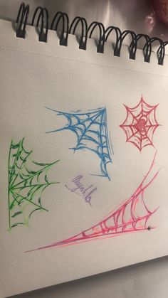 three spider webs are drawn on a piece of paper with colored crayons