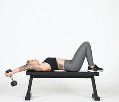 a woman is laying on a bench with a dumbbell in her hand and holding a barbell