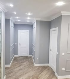 an empty room with wood flooring and white trim on the walls, painted in light gray