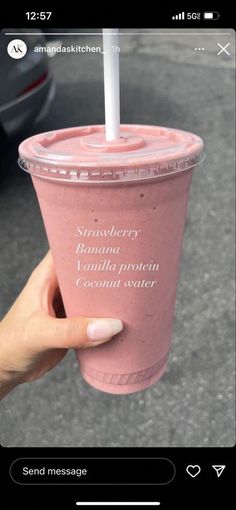 someone holding up a pink smoothie with a straw in it's cup that says, strawberry banana vanilla protein coconut water