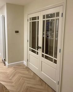 an empty room with white doors and wood flooring on the side of the wall