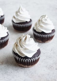 six cupcakes with white frosting sitting on top of a marble countertop