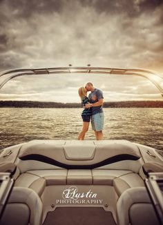 a man and woman kissing on the back of a boat in the water at sunset