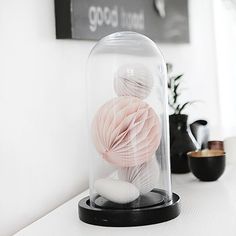 a clochet with some balls in it on a white shelf next to a potted plant