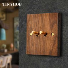 a wooden wall mounted light switch with two brass knobs