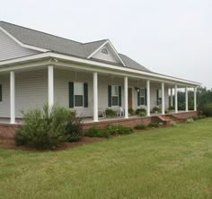 a gray house with white pillars and green shutters on the front porch is shown