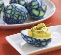 deviled eggs with green and blue glaze on white plates next to each other