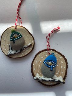 two ornaments made out of wood and decorated with snowman hats on top of each ornament