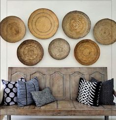 a wooden bench sitting in front of a wall filled with baskets on top of it