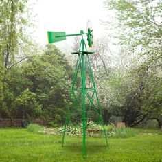 a green windmill sitting on top of a lush green field