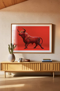 a red bull painting hanging on the wall above a wooden entertainment center with a potted plant