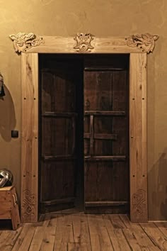 an open wooden door in a room with wood flooring and wall decorations on the walls