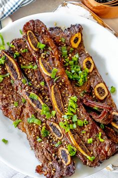 some meat is on a white plate with green garnishes and seasonings