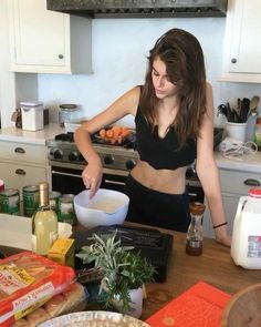 a woman mixing something in a bowl on top of a kitchen counter next to an oven