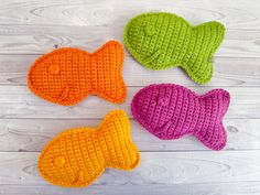 four crocheted fish on a white wooden surface