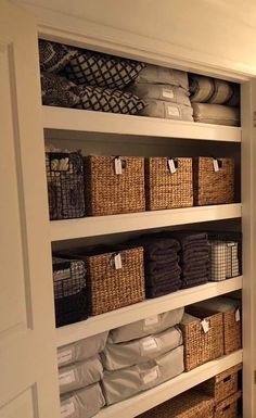 an organized closet with lots of baskets and towels on the shelves in front of it