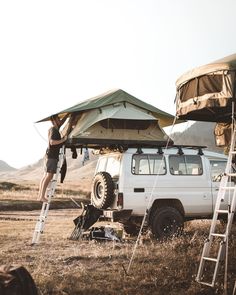 a man standing on top of a ladder next to a white truck under a tent